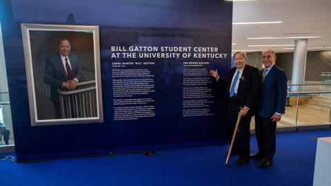 Eli Capilouto and Bill Gatton stand beside a wall of Gatton information